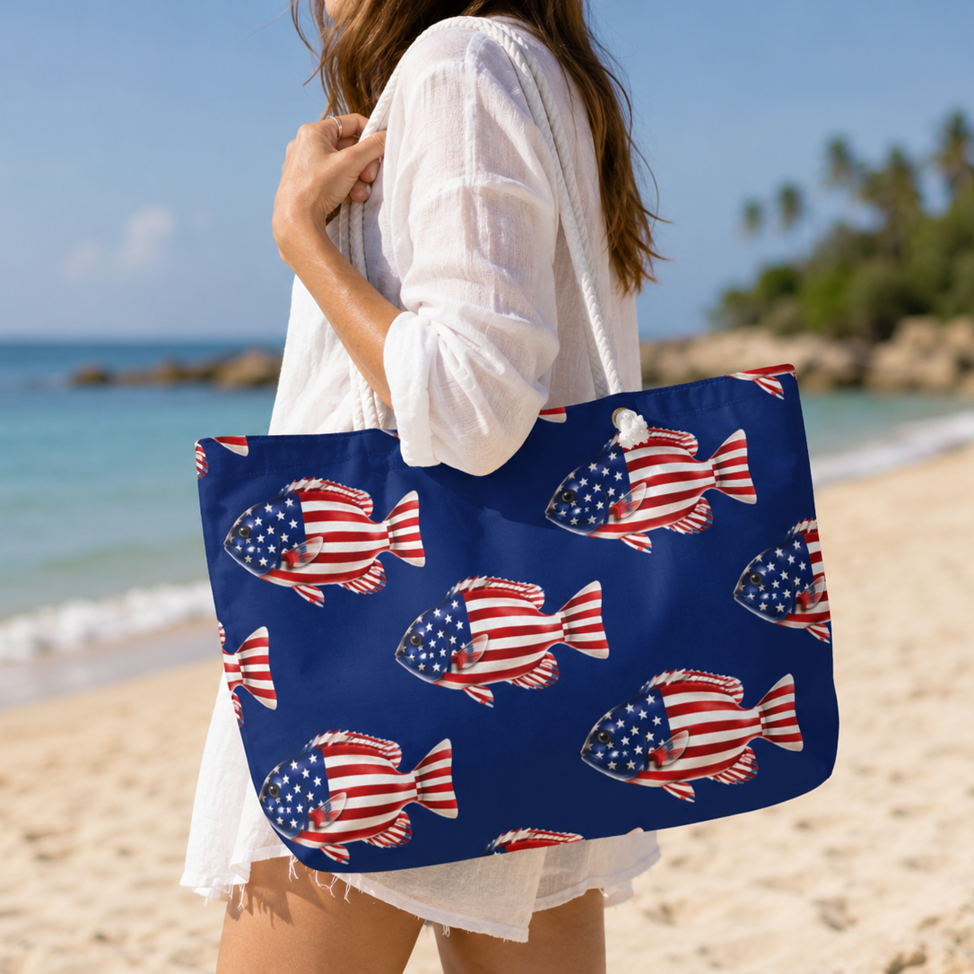 Person holding a blue tote bag with American flag fish pattern on a beach.