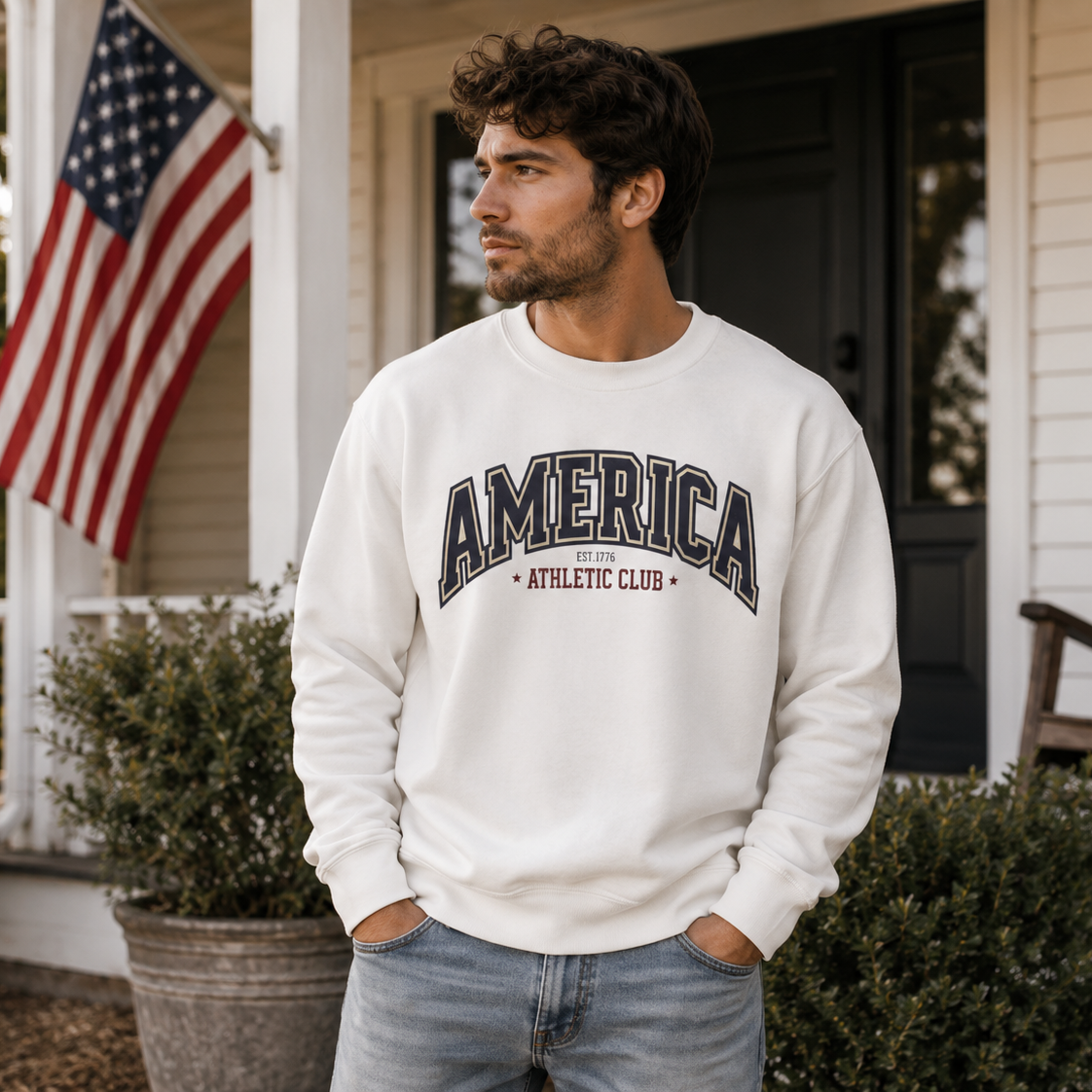 Man wearing a white sweatshirt with 'AMERICA ATHLETIC CLUB' text on a porch with an American flag.